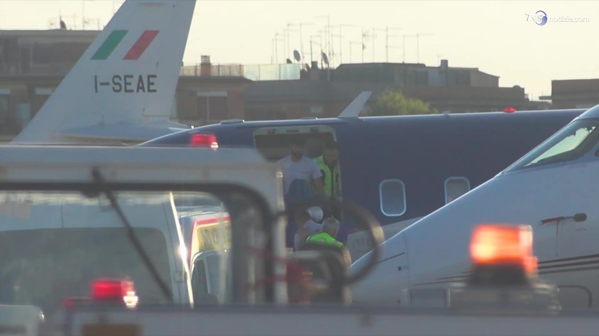 Di Battista portato fuori dall'aeroambulanza dai sanitari con la testa visibilmente fasciata