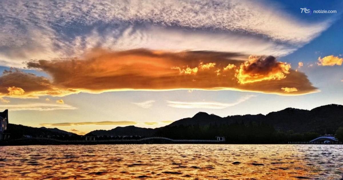Il tramonto infiamma il cielo dello Yunnan: nuvole rosse e riflessi d’oro sul lago